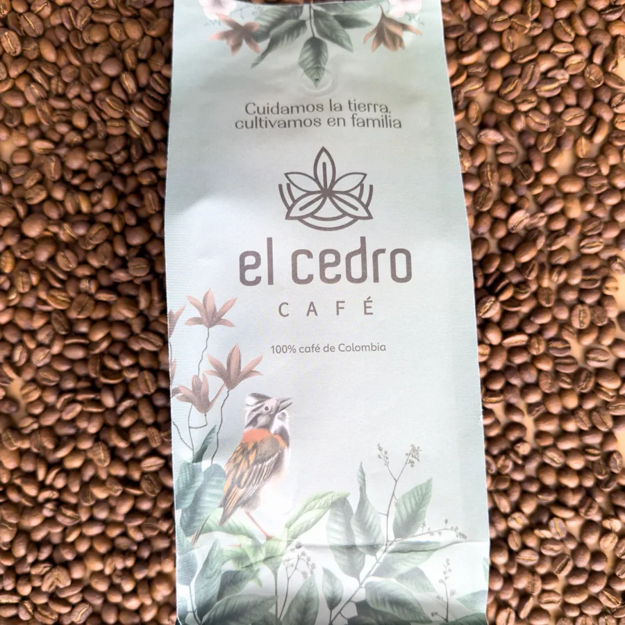 Bolsa de Café El Cedro sobre granos de café tostado.