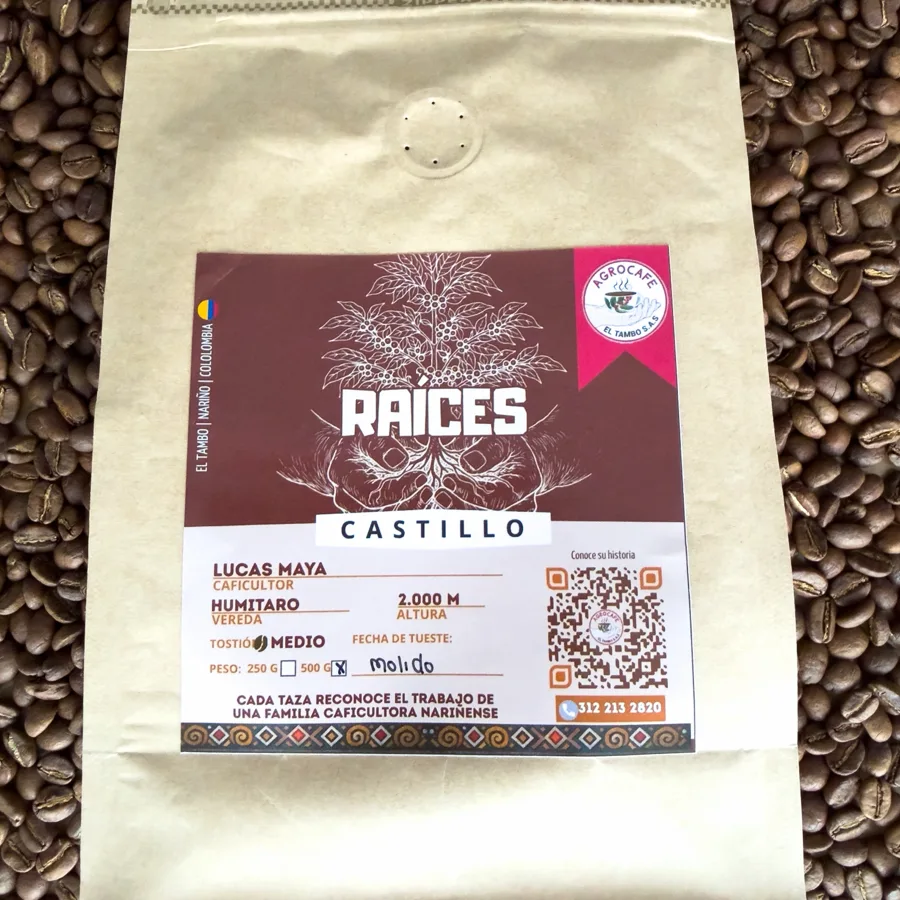 Bolsa de Café Raíces, con la etiqueta de Agrocafé El Tambo, sobre granos de café tostado.