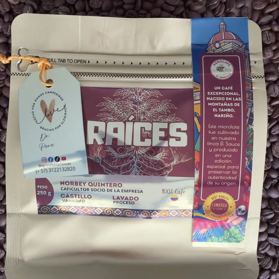 Bolsa de 250 g de Café Raíces, edición ganadora, con la tira de edición limitada de Agrocafé El Tambo, sobre granos de café tostado.